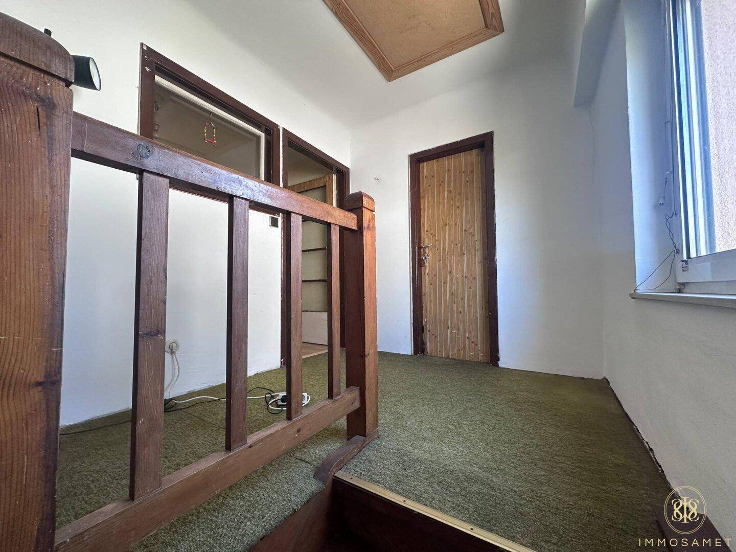 Obergeschoss-Flur mit Teppichboden und Holztüren, bietet Zugang zu den Zimmern.