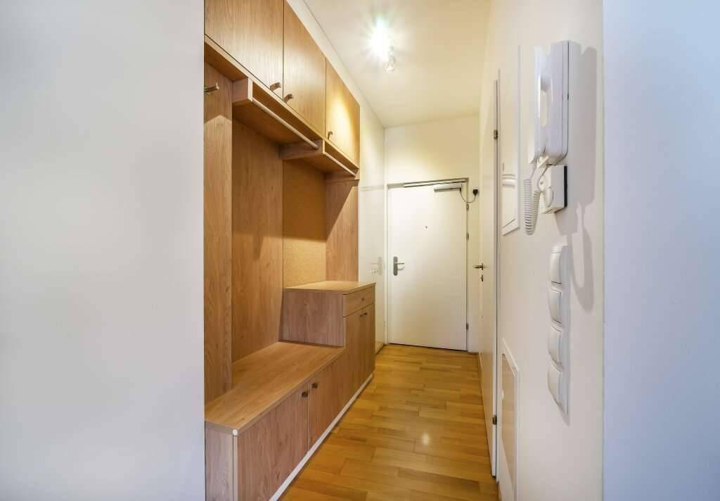 Funktionaler Eingangsbereich mit Holz-Einbaumöbeln, Garderobe und Gegensprechanlage.