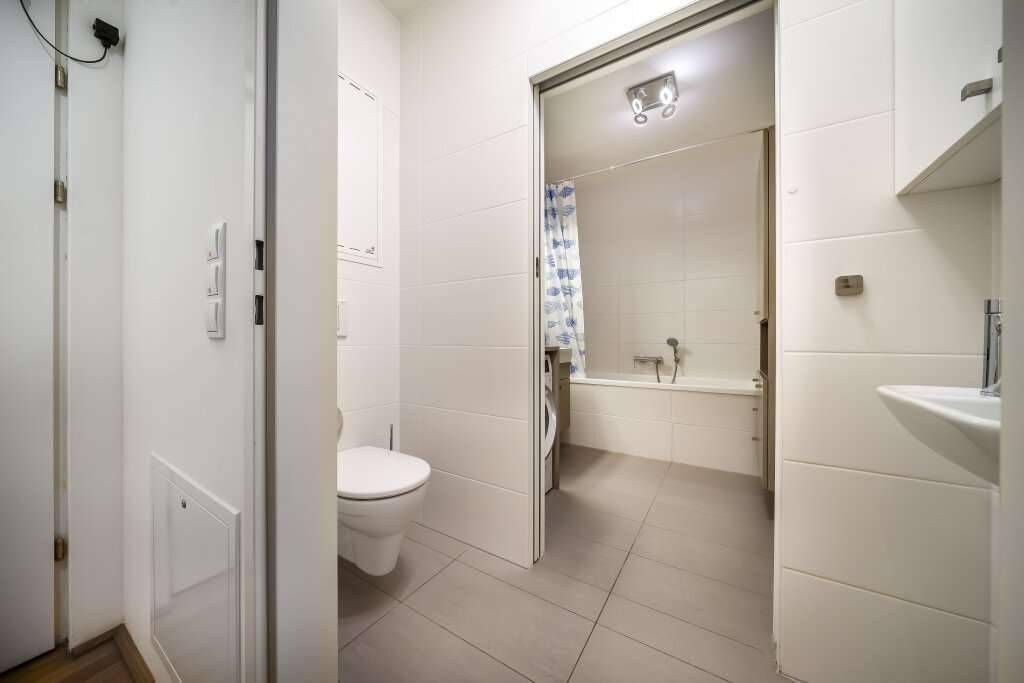 Modernes Badezimmer mit Wand-WC und Zugang zu einer Badewanne mit Duschvorhang.