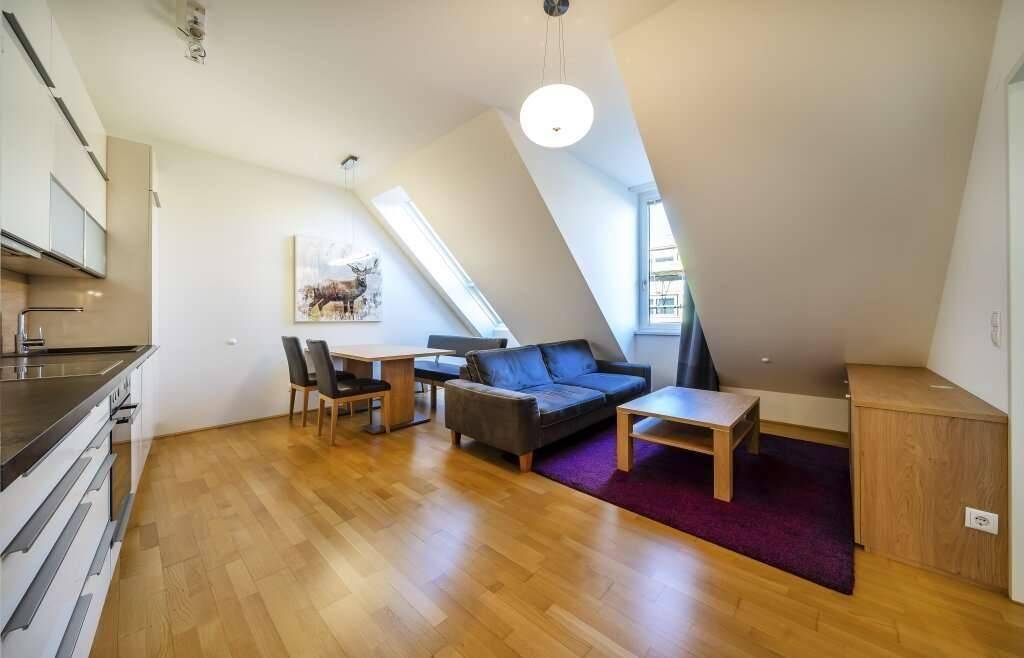 Gemütlicher Wohnbereich mit Sofa, Couchtisch und Fenster, ergänzt durch eine moderne Küche.