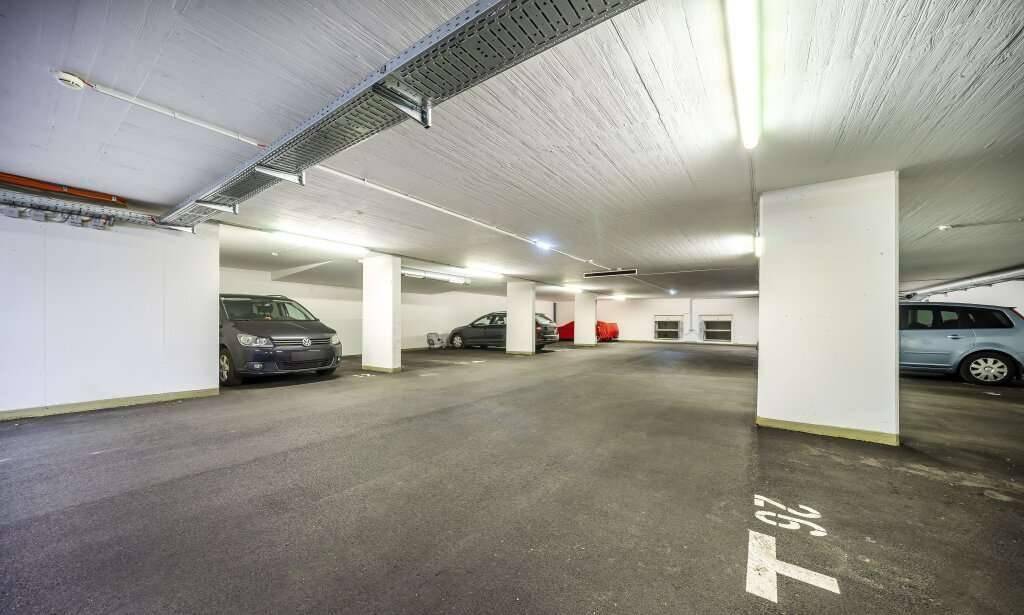 Geräumige Tiefgarage mit mehreren Stellplätzen und geparkten Fahrzeugen.