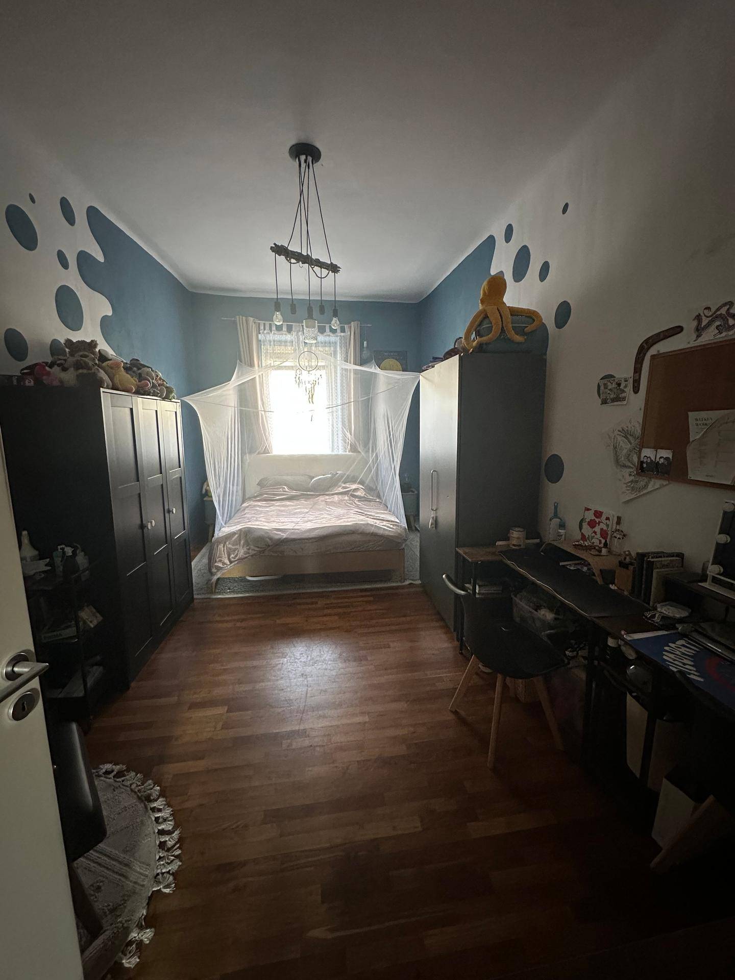 Schlafzimmer mit Holzboden, Doppelbett und farbenfroher Wandgestaltung.
