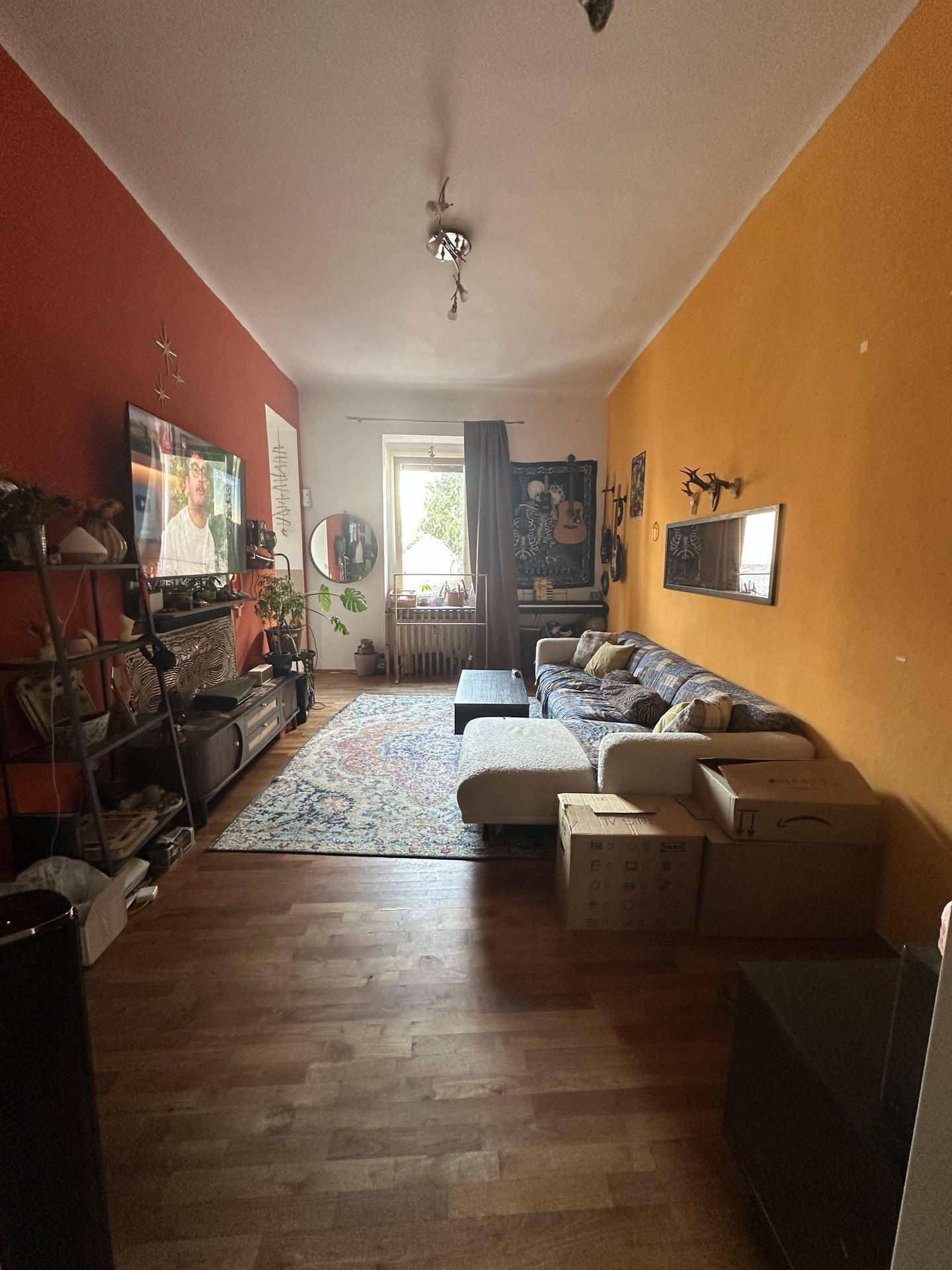 Gemütliches Wohnzimmer mit Holzboden, Fernseher und Fenster mit Blick nach draußen.