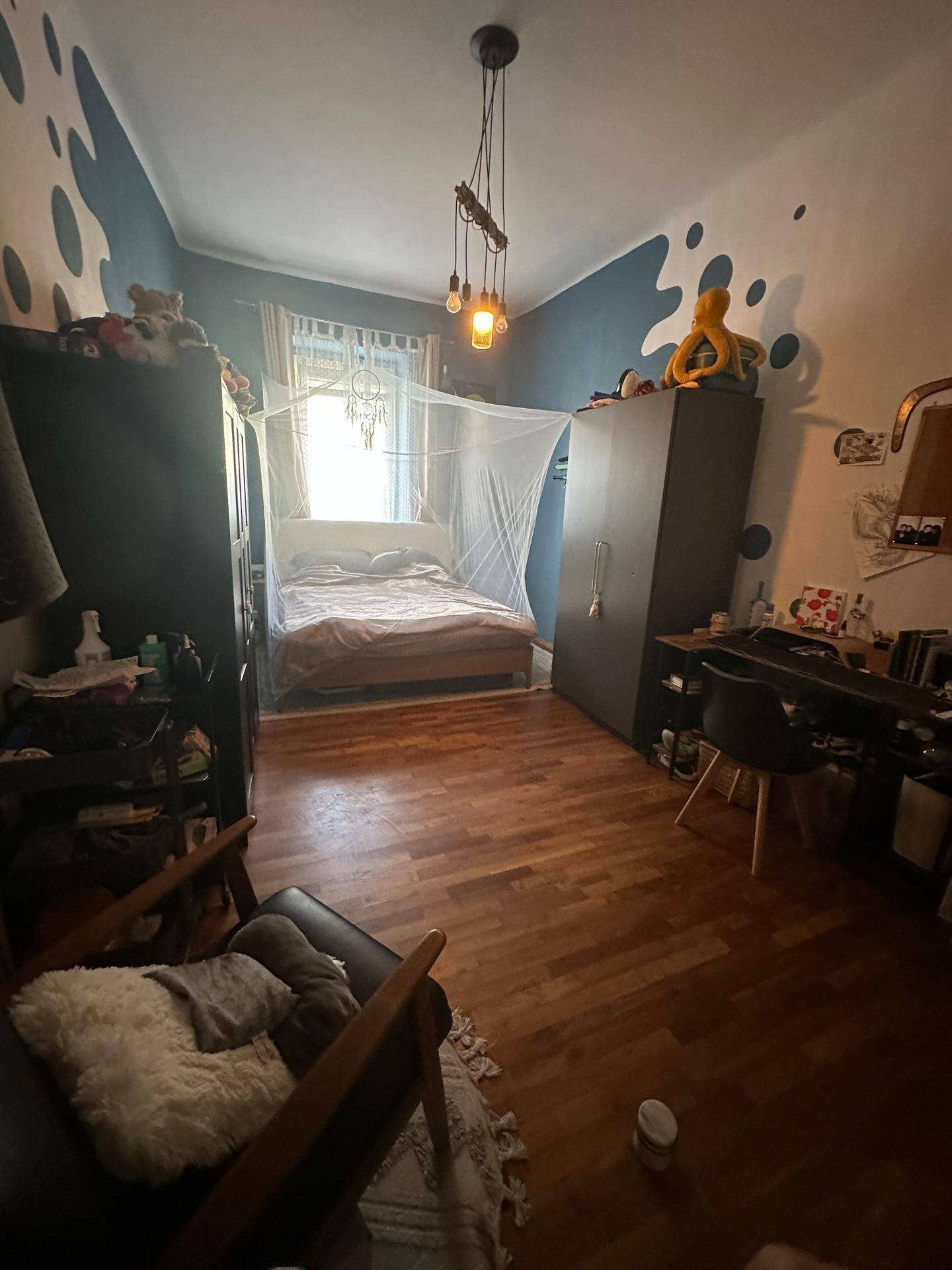 Gemütliches Schlafzimmer mit Holzboden, Bett mit Moskitonetz und Schränken.