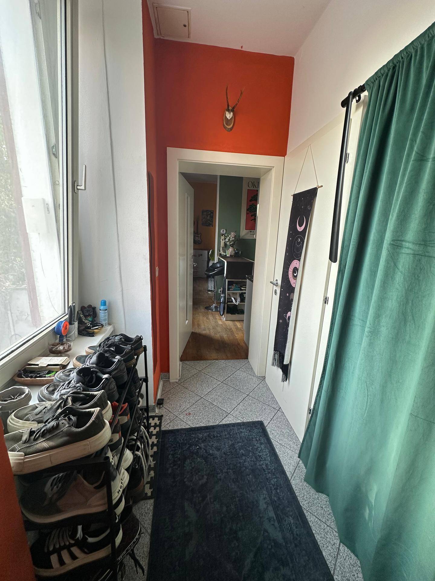 Heller Flur mit Fliesenboden, Schuhregal und Zugang zu weiteren Räumen.
