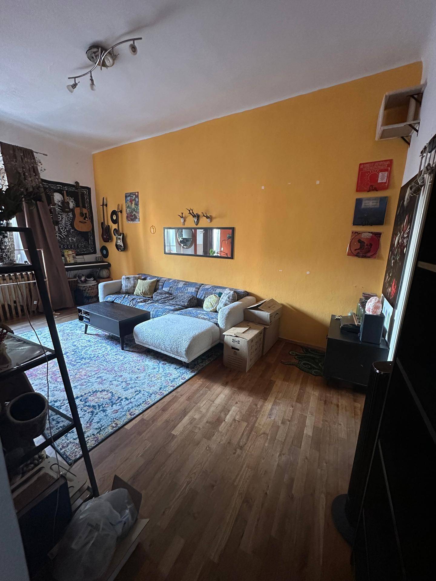 Helles Wohnzimmer mit Holzboden, bequemer Couch und individueller Wandgestaltung.