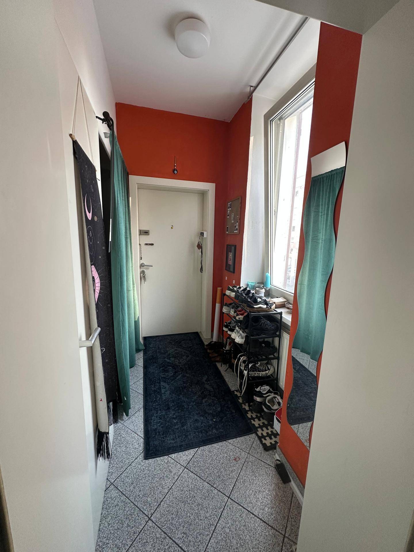 Eingangsbereich mit Fliesenboden, großem Fenster und praktischem Schuhregal.