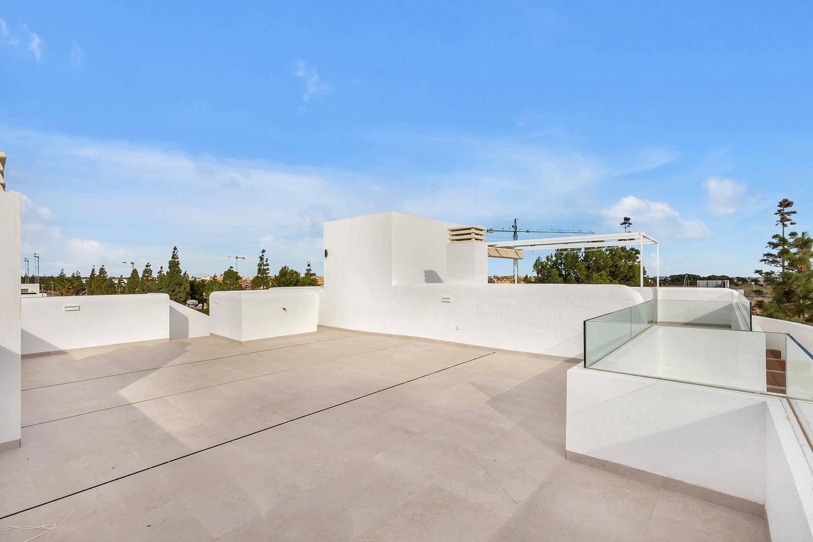 Geräumige Dachterrasse mit weißer Brüstung und weitem Blick über die Dächer.