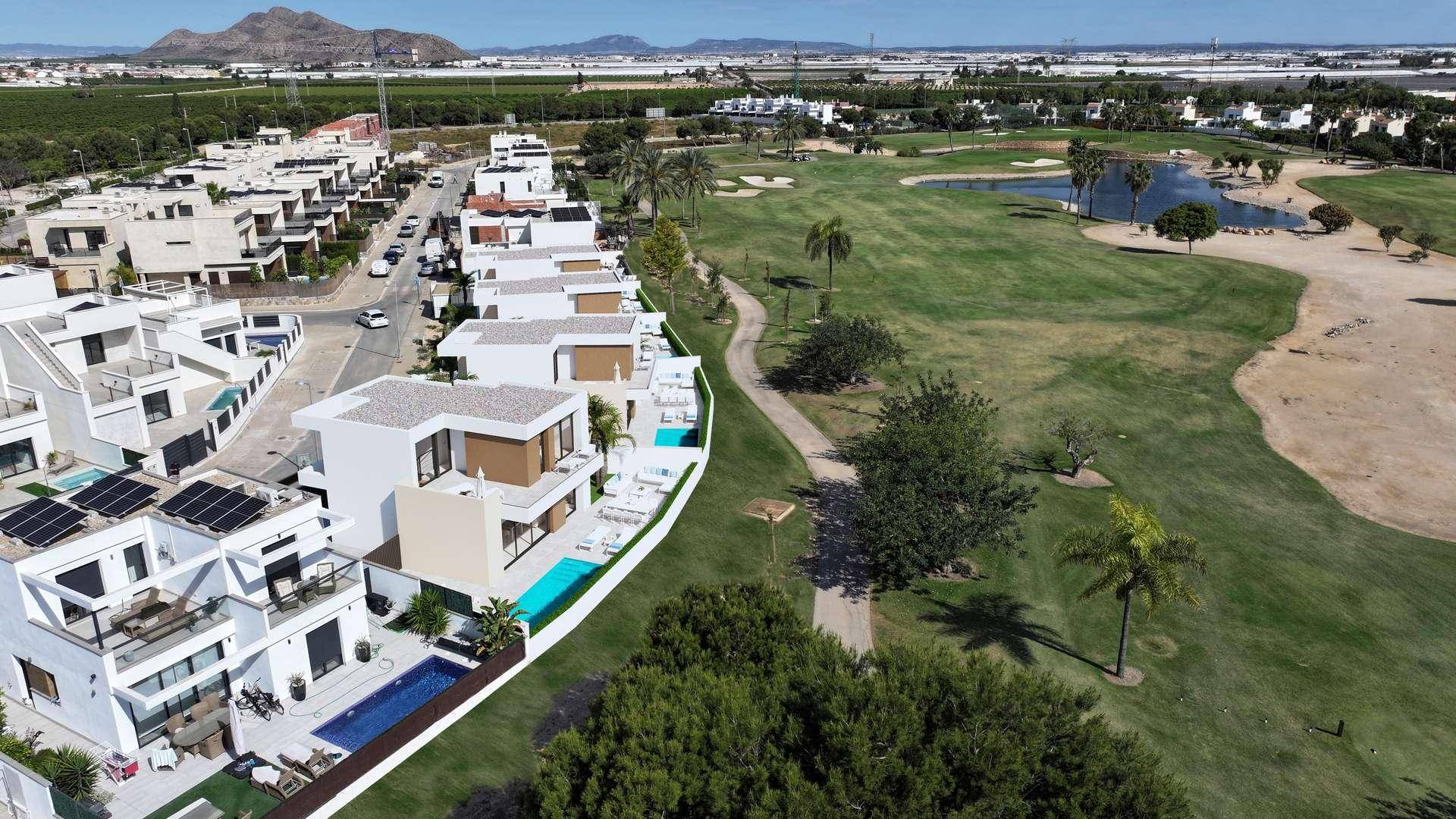 Weitläufige Luftaufnahme einer modernen Wohnanlage mit Pools und angrenzendem Golfplatz.