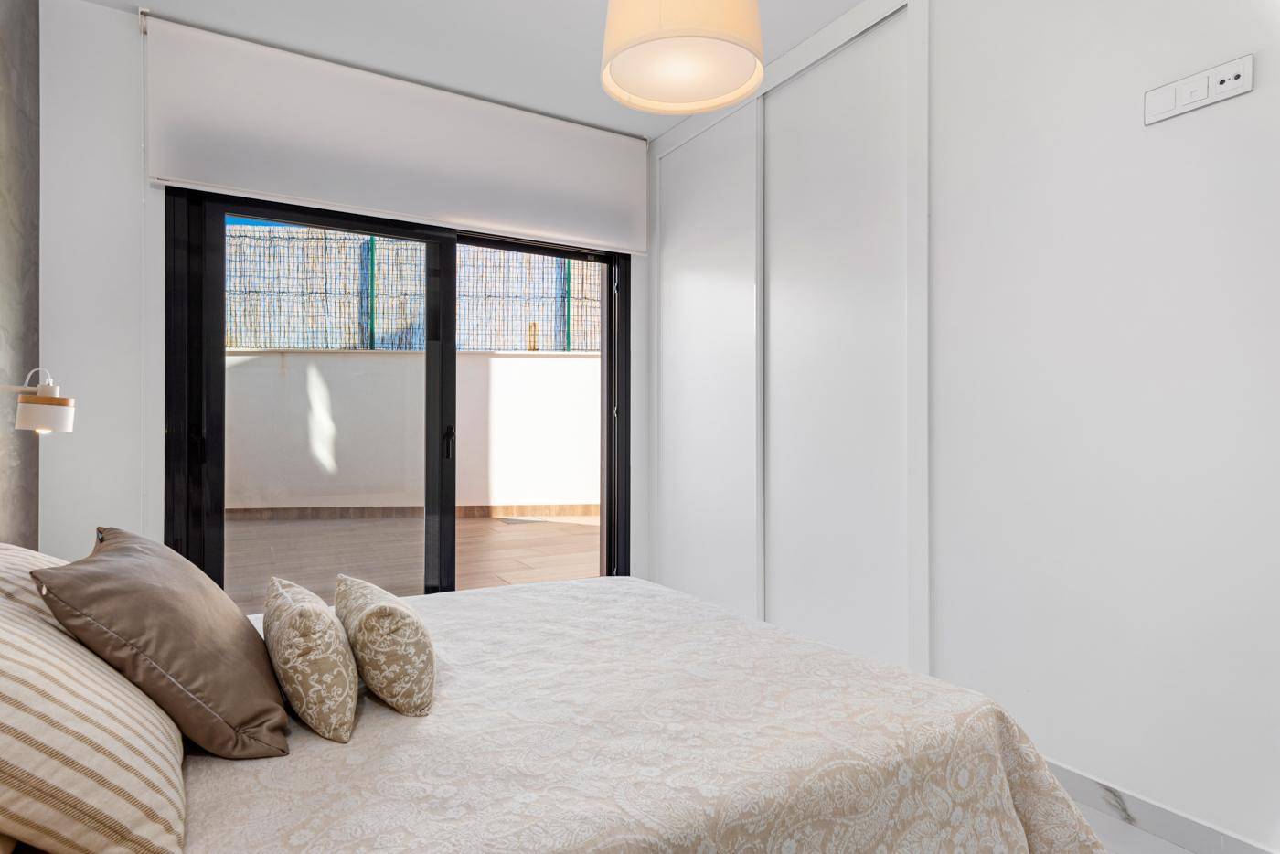 Schlafzimmer mit Einbauschrank und Schiebetür zum Außenbereich, hell und modern.