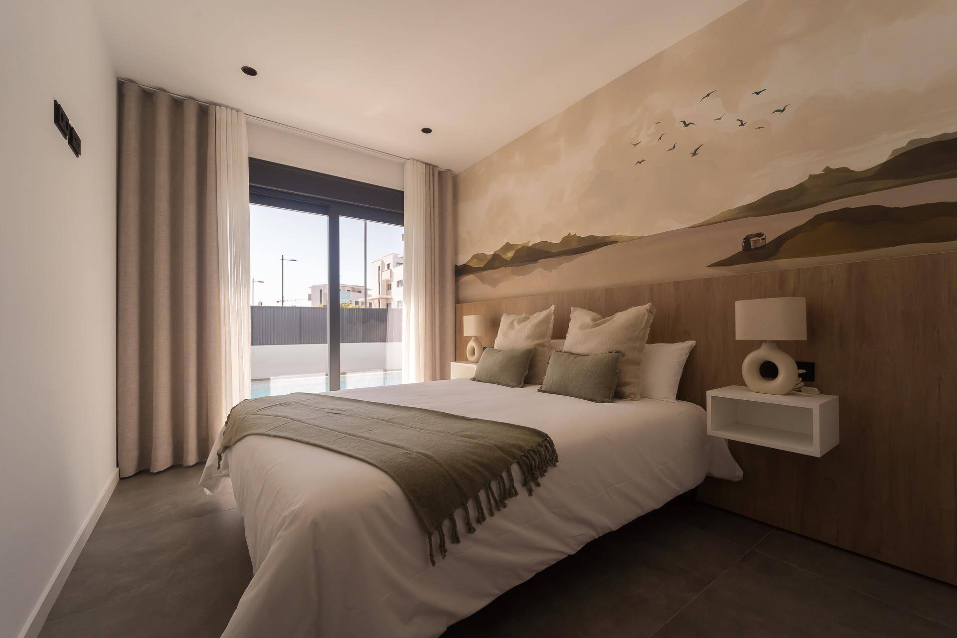 Gemütliches Schlafzimmer mit Doppelbett, Wandgemälde und Zugang zur Terrasse.