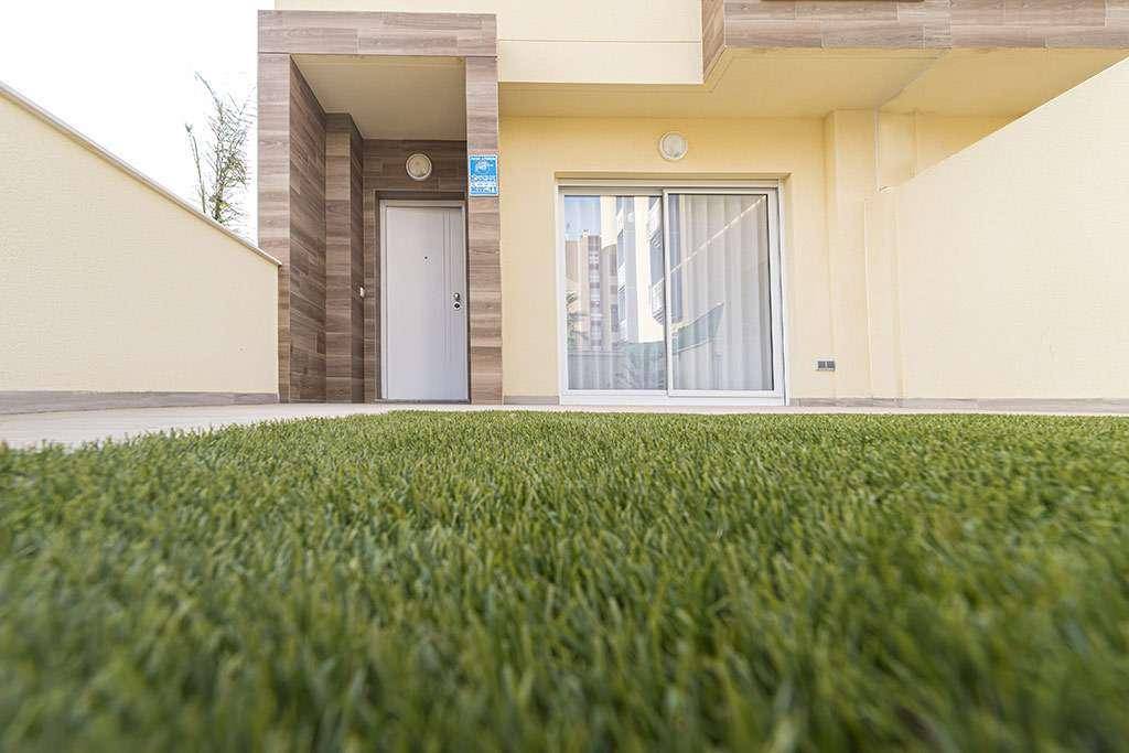 Eingangsbereich eines modernen Hauses mit Kunstrasen und Schiebetür zur Terrasse.