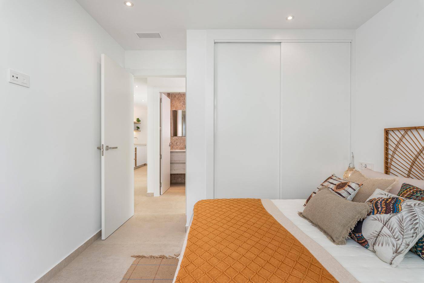 Schlafzimmer mit Einbauschränken und Zugang zu einem modernen Badezimmer.