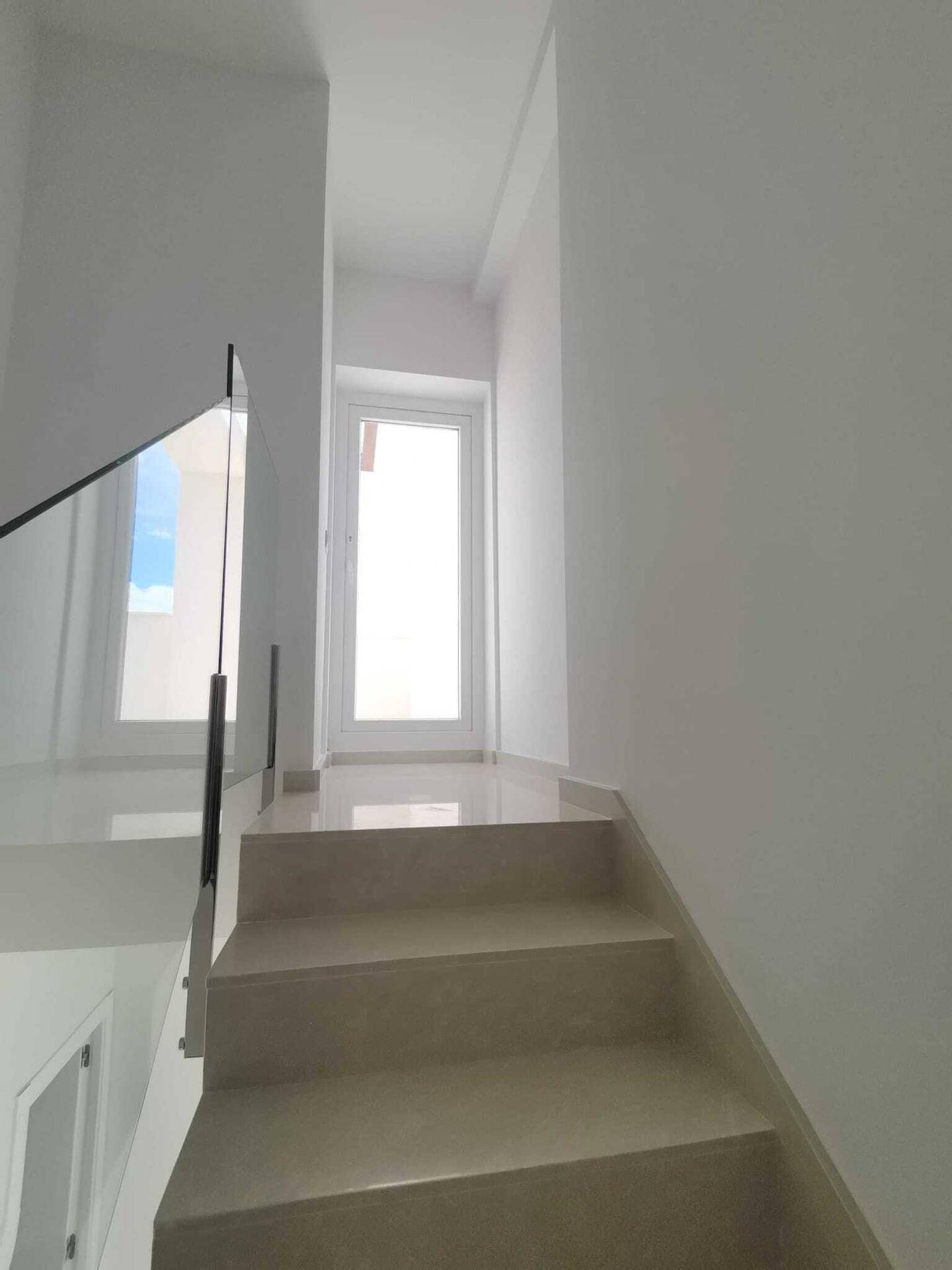 Moderne Treppe mit Glasgeländer und hellem Marmorboden, die die Etagen elegant verbindet.