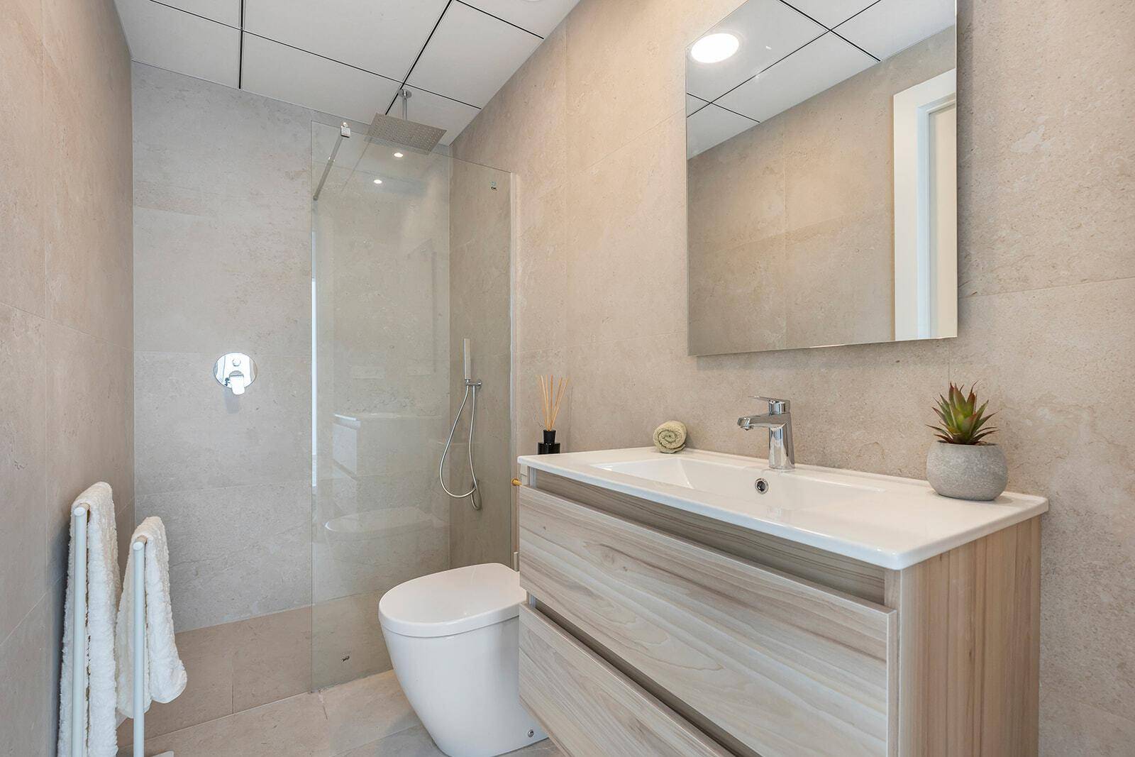 Modernes Badezimmer mit begehbarer Dusche, Wand-WC und eleganten Fliesen in Naturtönen.