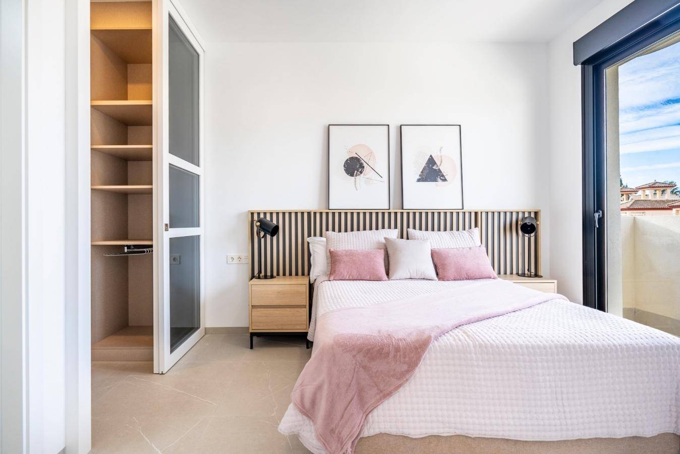 Modernes Schlafzimmer mit Doppelbett, Holzkopfteil, Einbauschrank und Zugang zu einem Balkon.