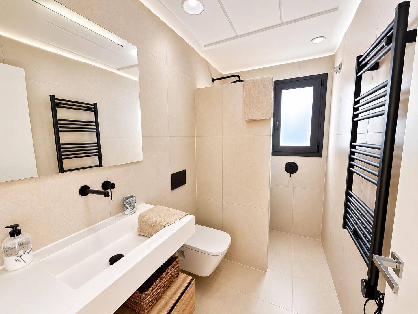 Modernes Badezimmer mit beigefarbenen Fliesen, wandhängendem WC und beheiztem Handtuchhalter.
