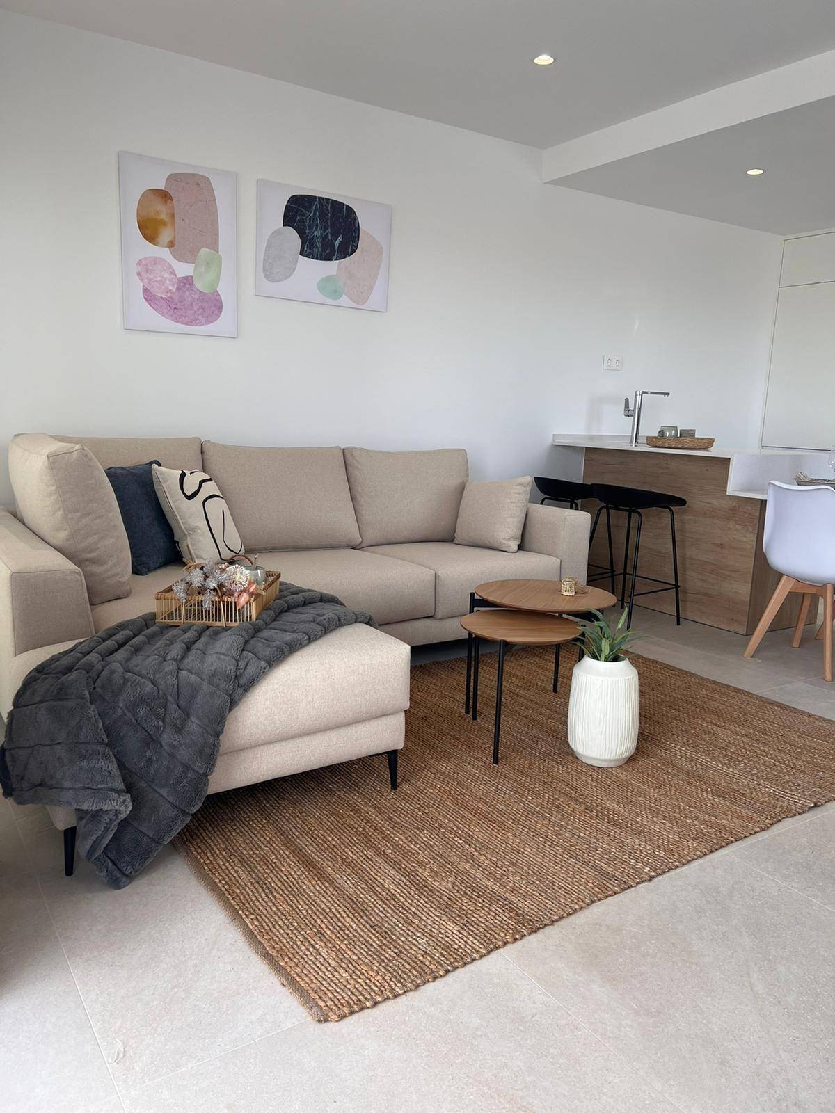 Moderner Wohnbereich mit beigem Ecksofa, Holztischen und minimalistischer Dekoration.