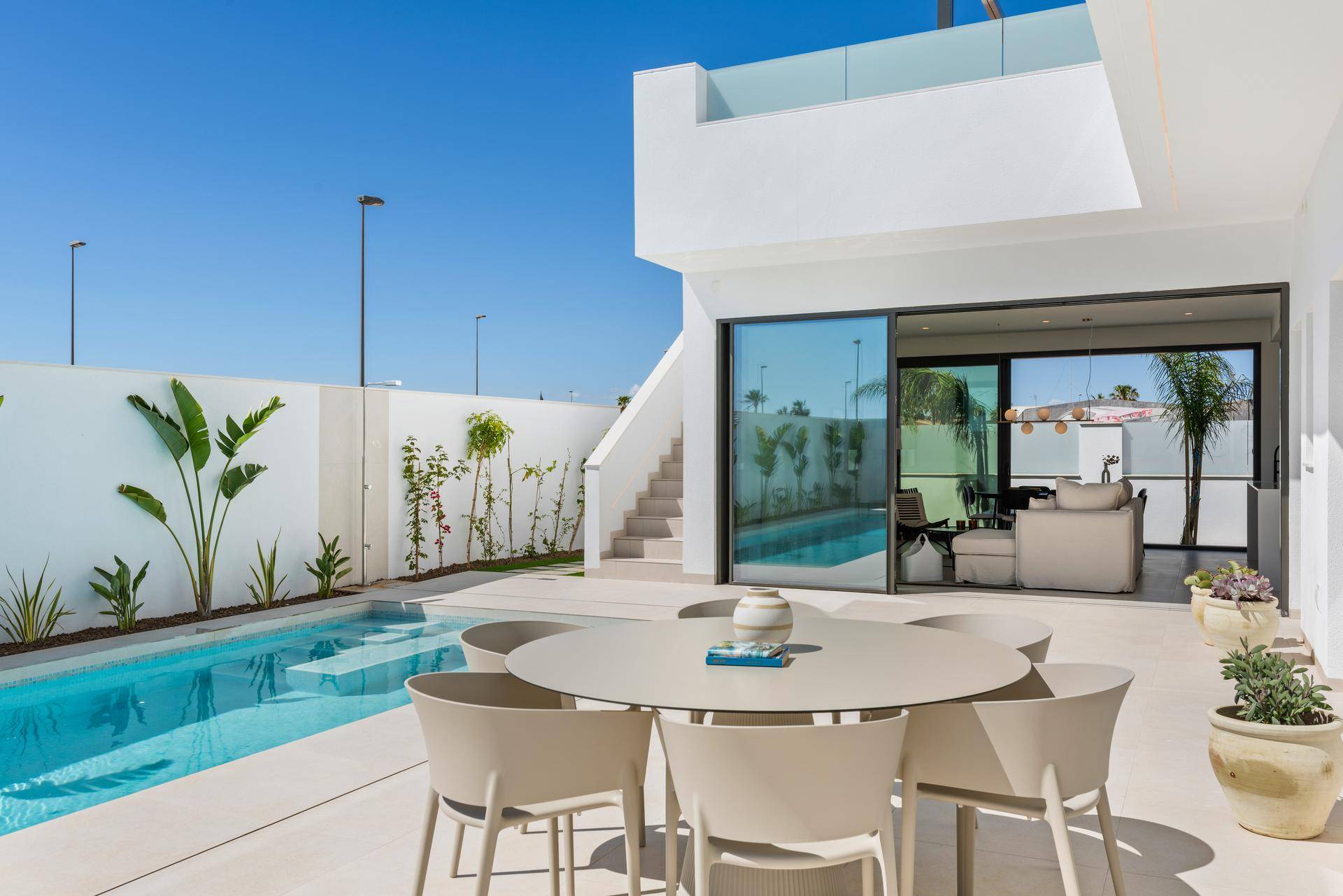 Großzügige Terrasse mit Esstisch und Stühlen, direkt am Poolbereich eines modernen Hauses.