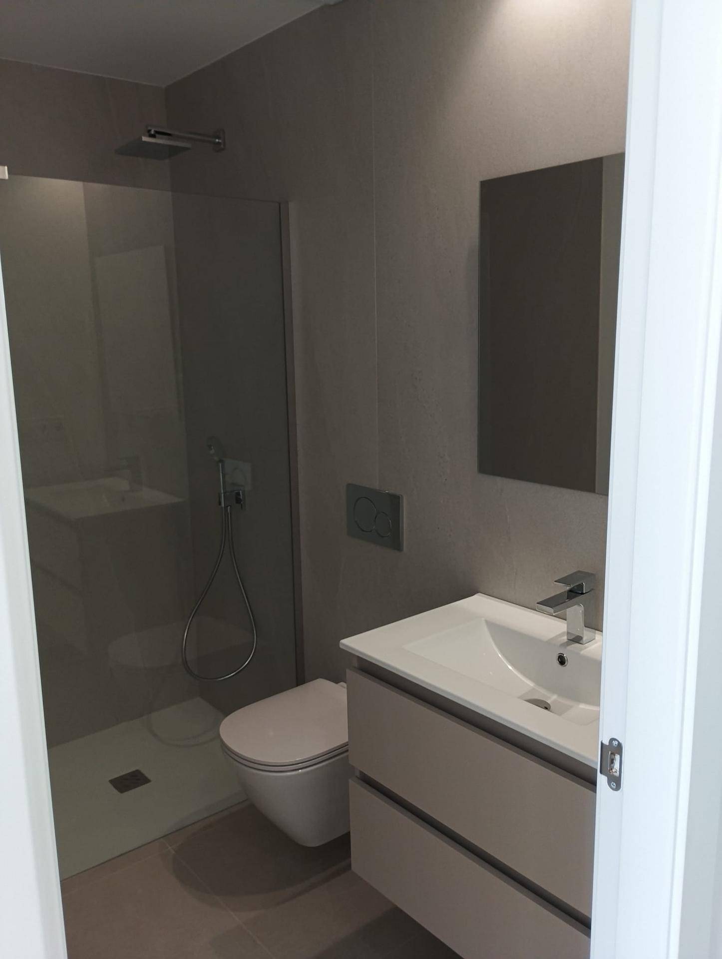 Modernes Gäste-WC mit kleinem Waschtisch, Spiegel und Wand-WC in minimalistischem Design.