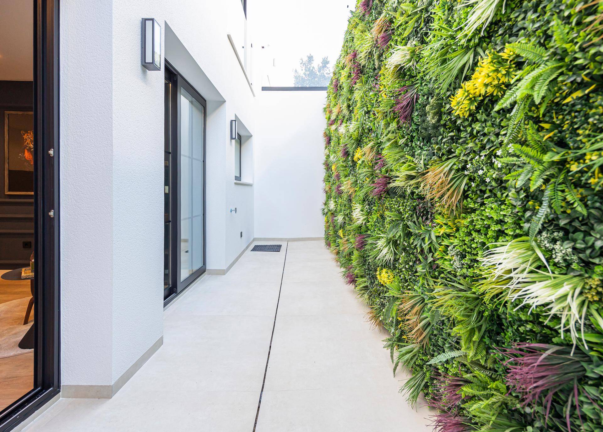 Außenbereich mit vertikalem Garten und modernem Design entlang eines Gehwegs.