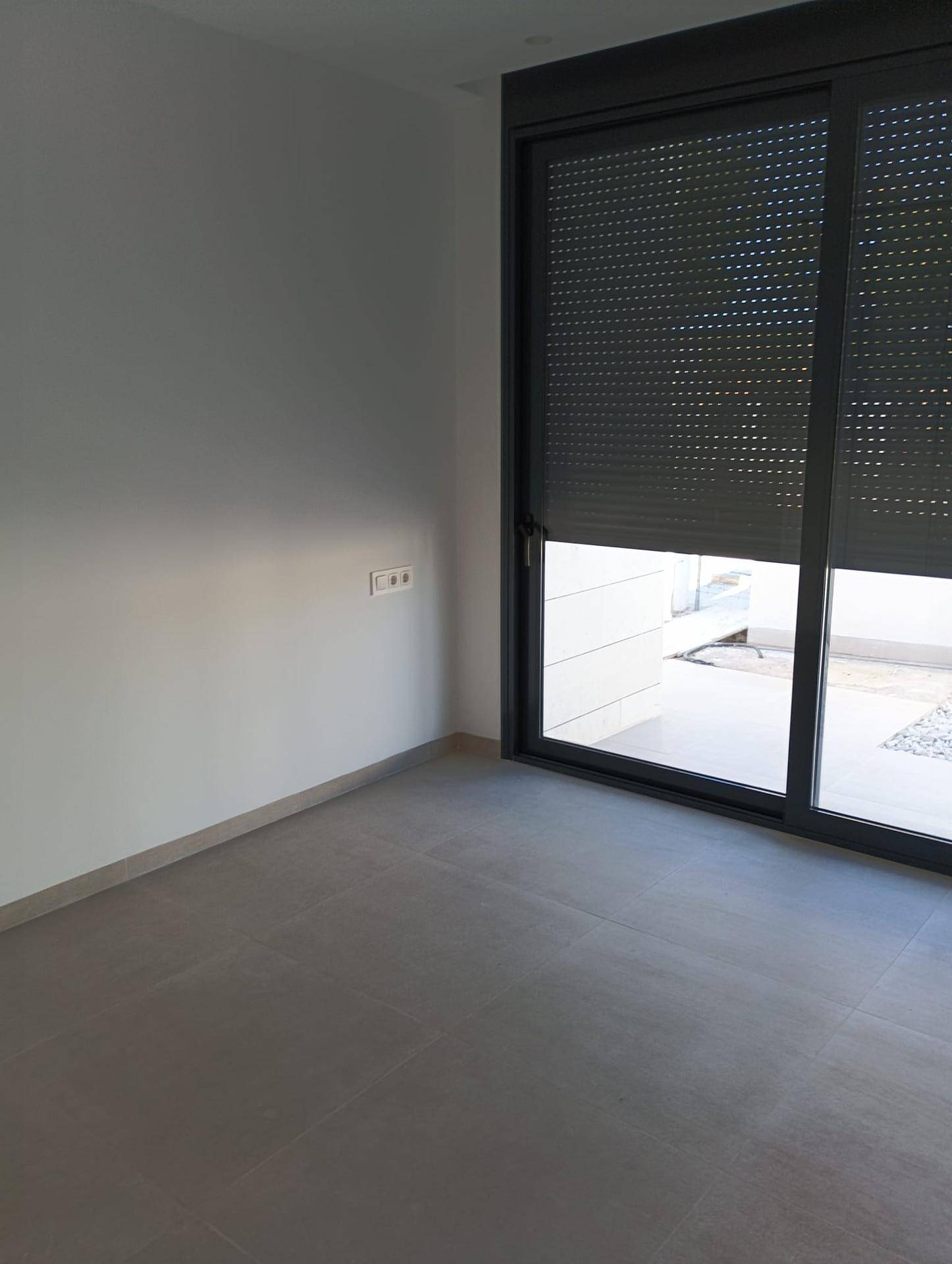 Helles Zimmer mit großen Schiebefenstern und Rollläden, bietet viel Tageslicht.