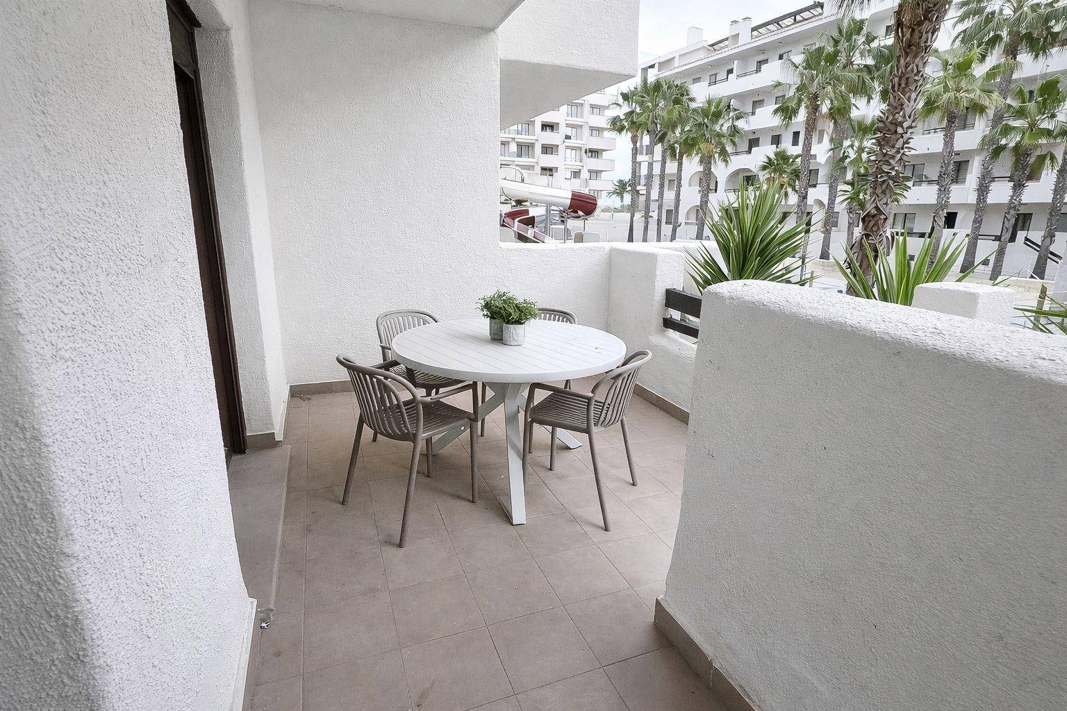 Gemütlicher Balkon mit Esstisch und Stühlen, umgeben von Palmen und Blick auf die Anlage.