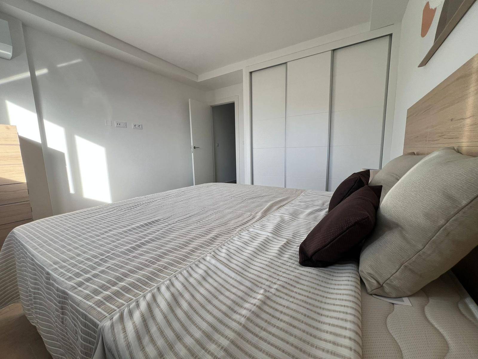 Gemütliches Schlafzimmer mit Doppelbett, Einbauschrank und viel natürlichem Licht.