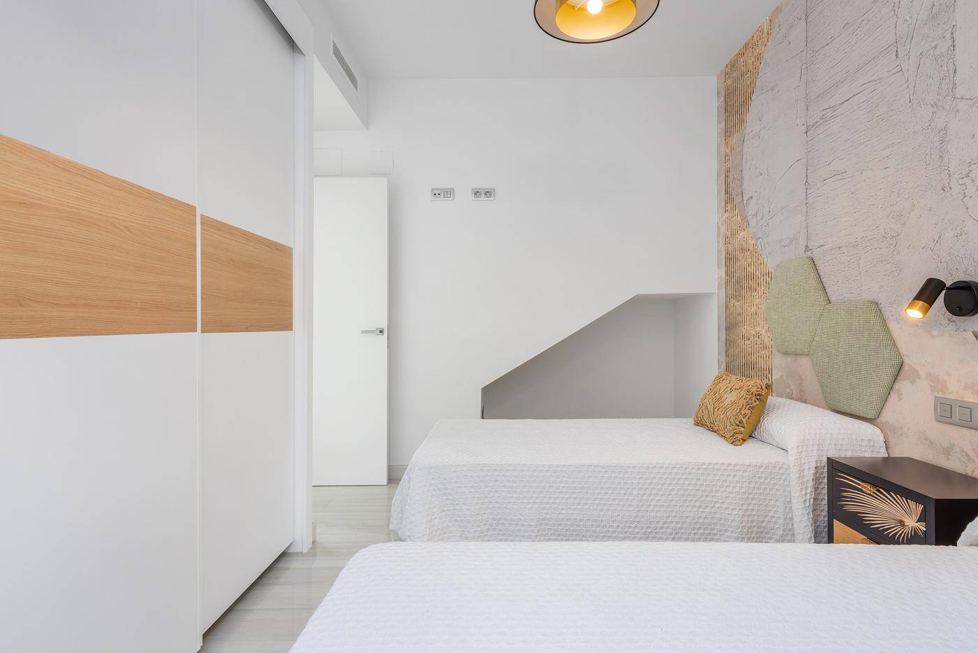 Schlafzimmer mit zwei Einzelbetten, moderner Wandgestaltung und integriertem Schrank.