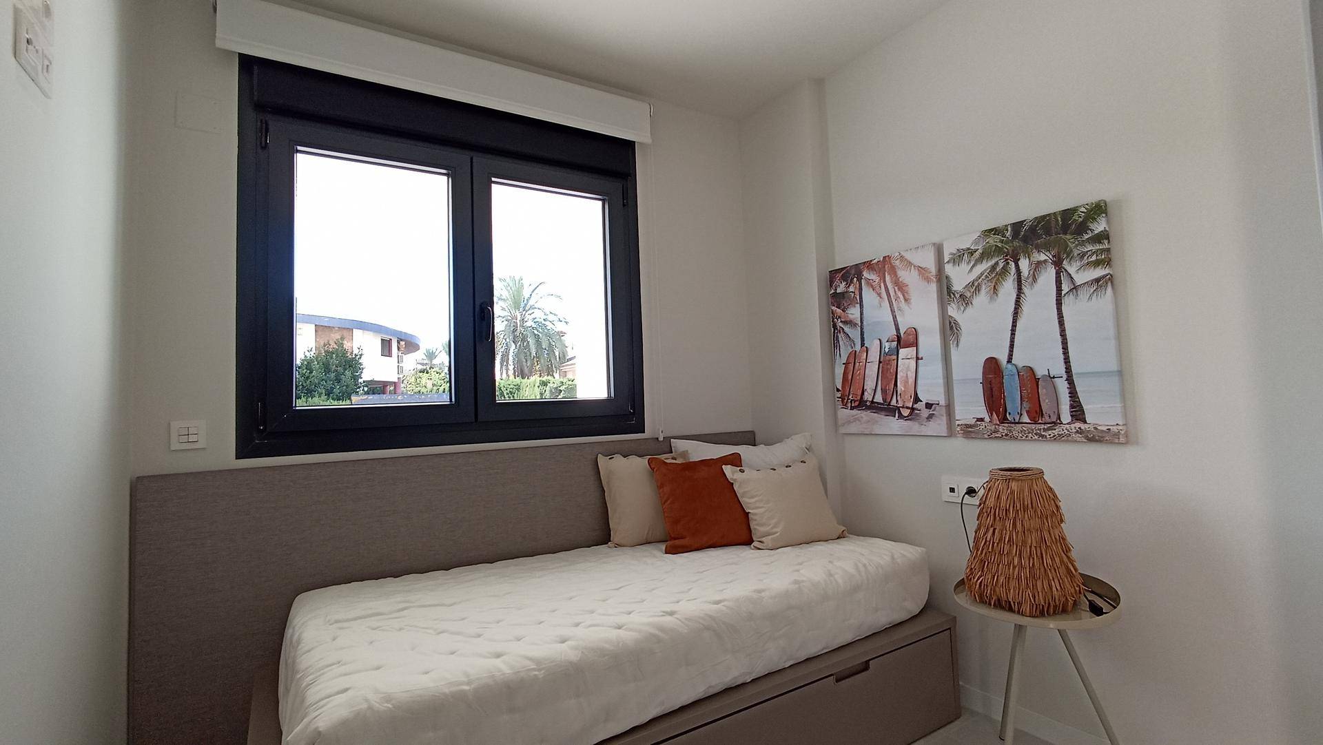 Helles Schlafzimmer mit Einzelbett, Fenster und tropischen Wandbildern.