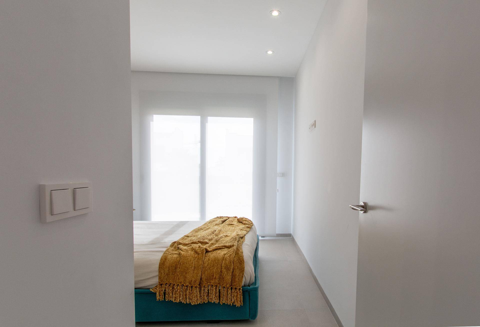 Helles Schlafzimmer mit großem Fenster, das viel Tageslicht hereinlässt.