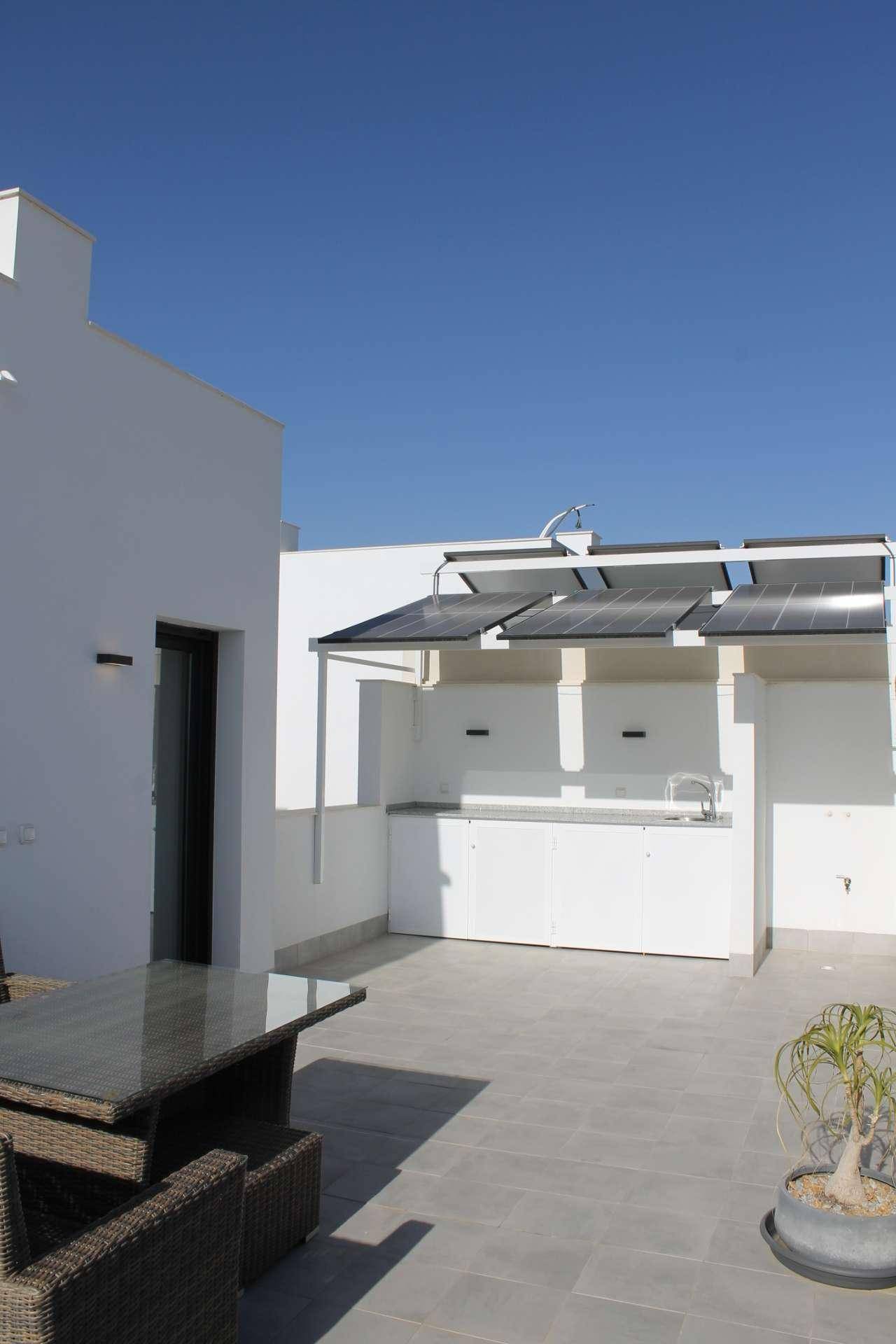 Sonnige Dachterrasse mit Außenküche, Essbereich und Photovoltaik-System.