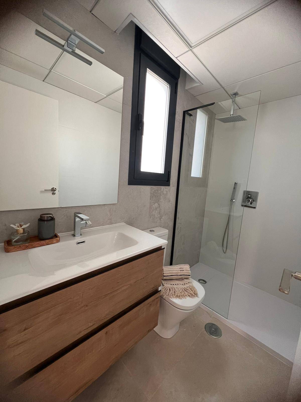 Modernes Badezimmer mit begehbarer Dusche, Holzwaschtisch und Fenster für Tageslicht.