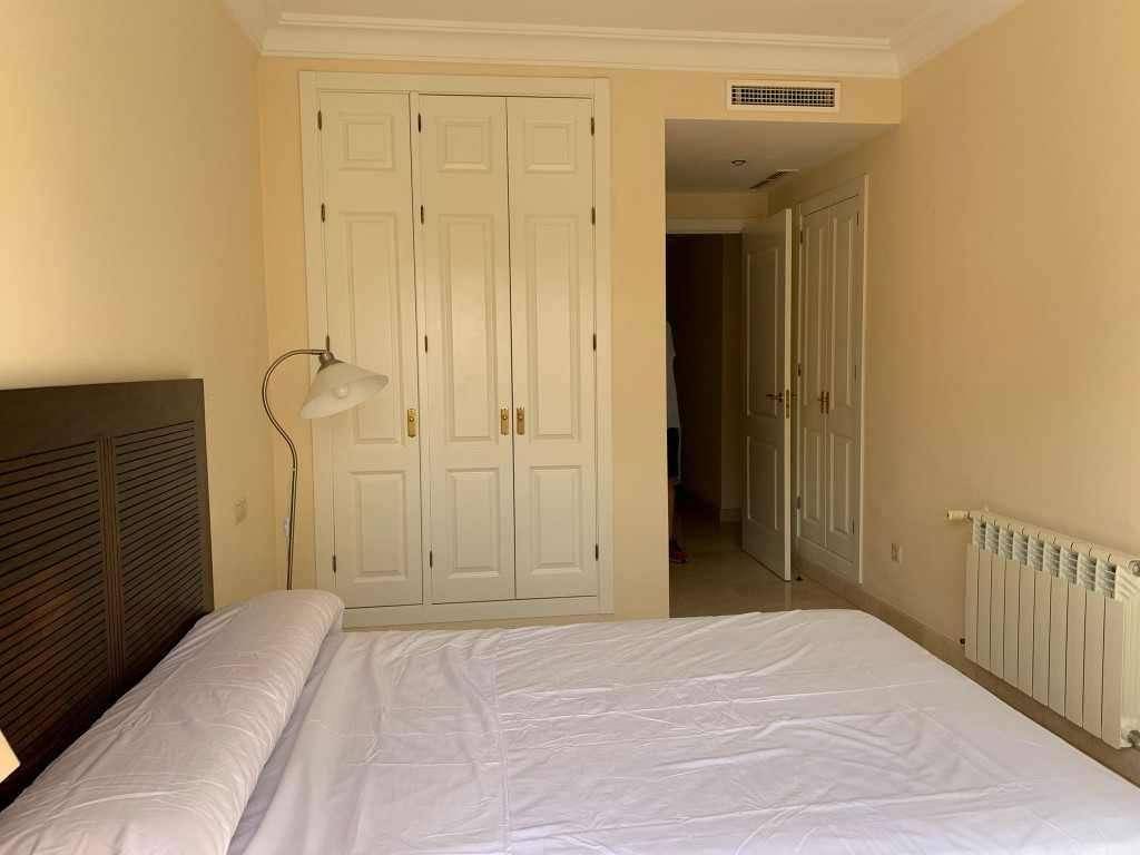 Schlafzimmer mit integrierten weißen Kleiderschränken und Marmorboden.