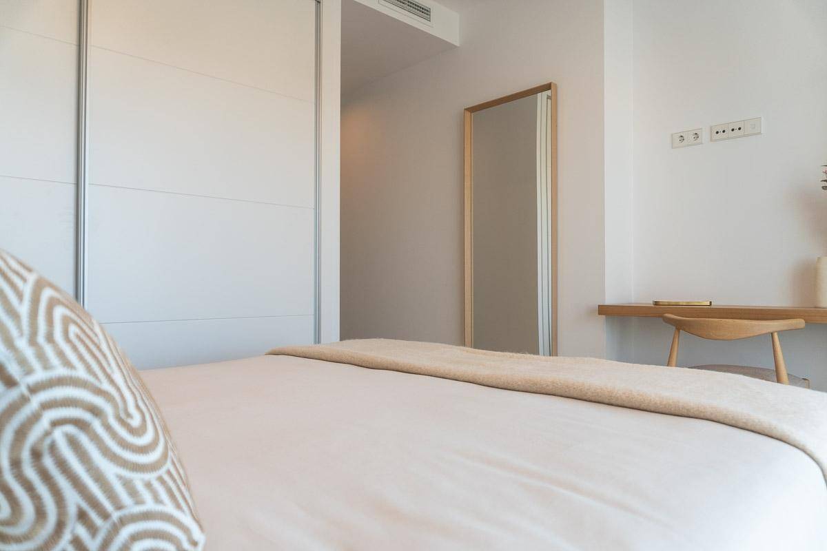 Detailansicht eines Doppelbettes mit Einbauschrank und einem großen Spiegel im Schlafzimmer.