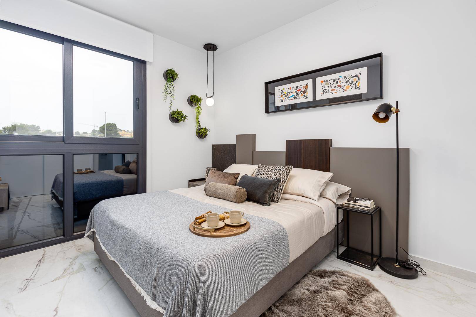 Helles Schlafzimmer mit modernem Doppelbett und großem Fenster für viel Tageslicht.