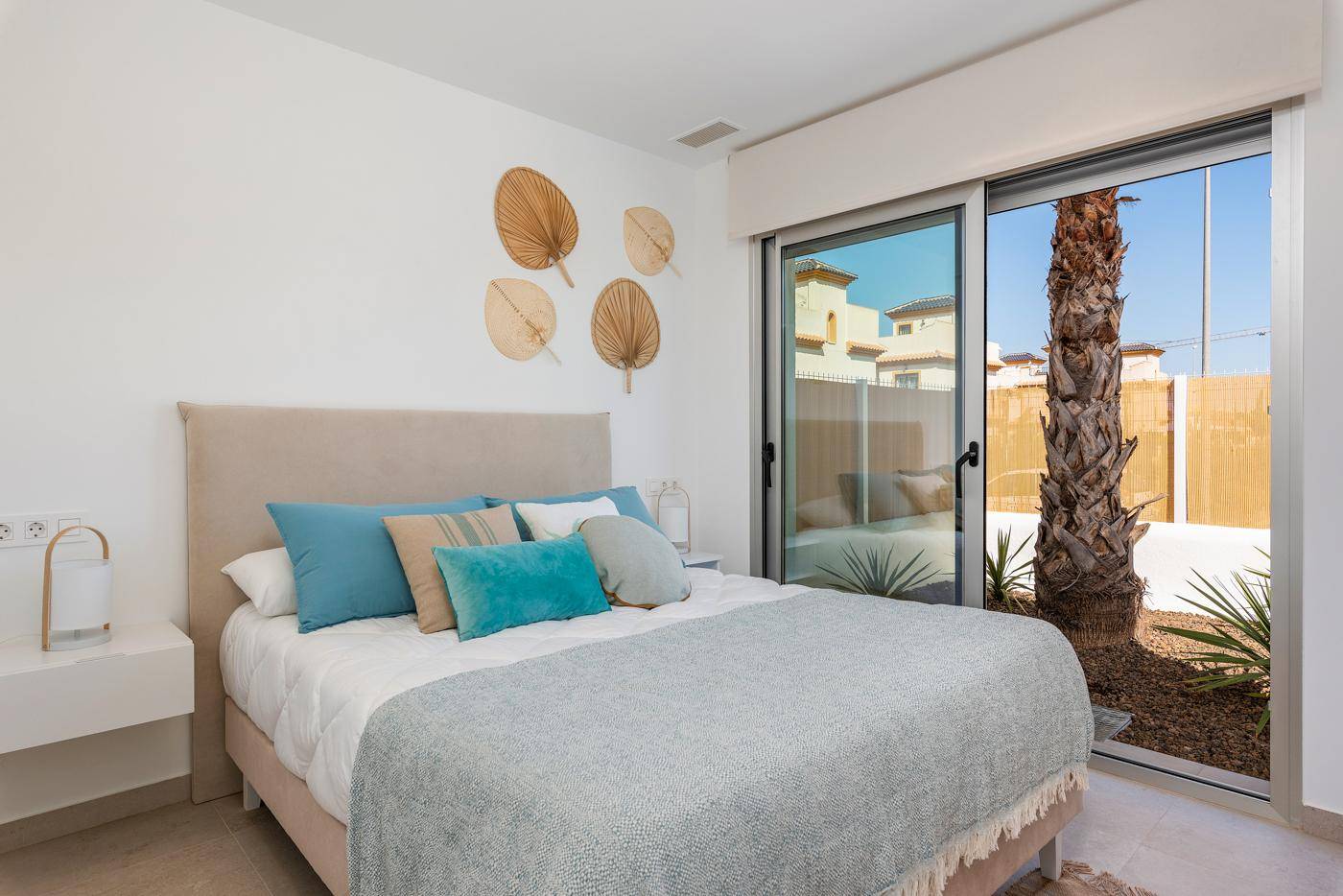 Helles Schlafzimmer mit Schiebetür zum Garten und dekorativer Palme, modern gestaltet.