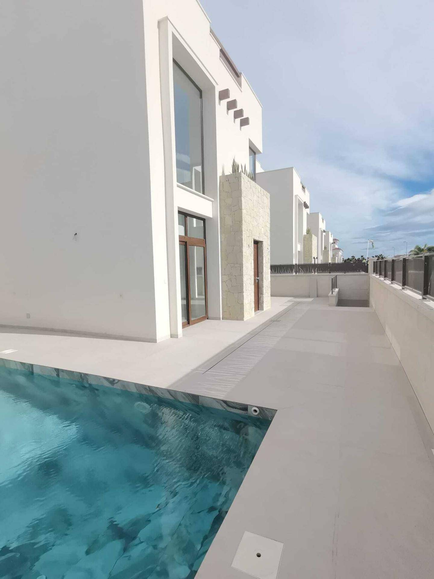 Moderne Gebäudeseite mit privatem Pool und minimalistischer Gestaltung unter blauem Himmel.