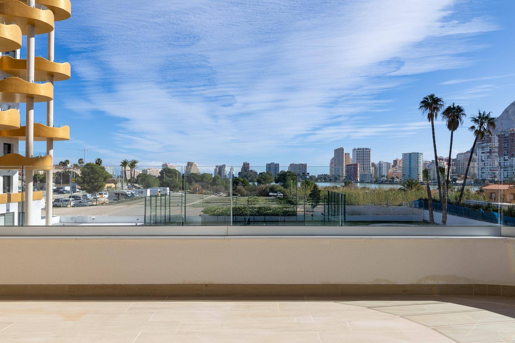 Weitläufige Terrasse mit Panoramablick auf die Stadt, Palmen und das Meer im Hintergrund.