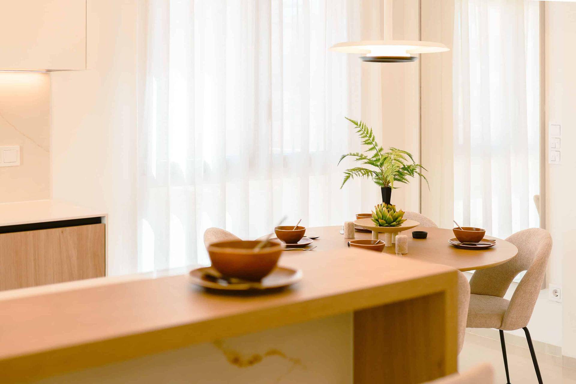 Heller Essbereich mit rundem Holztisch und modernen Stühlen, offen zum Wohnbereich.