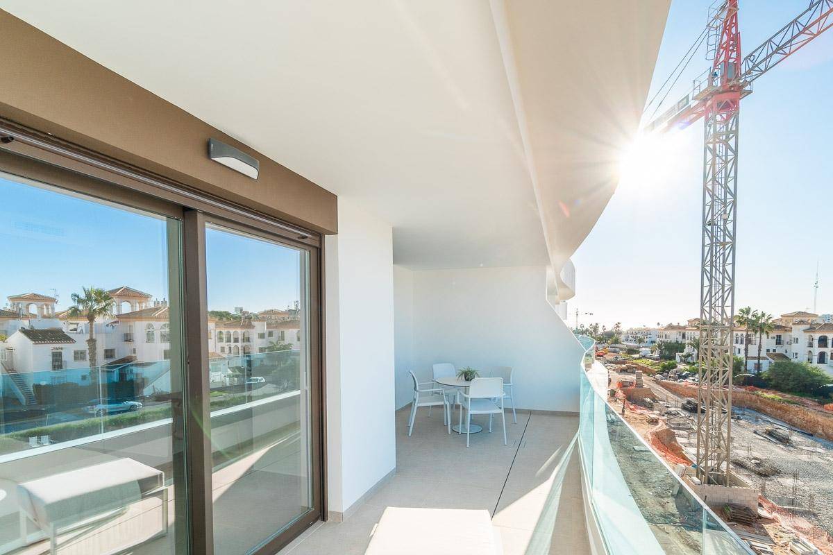Heller Balkon mit Esstisch und Stühlen, Glasgeländer und sonnigem Blick auf die Umgebung.