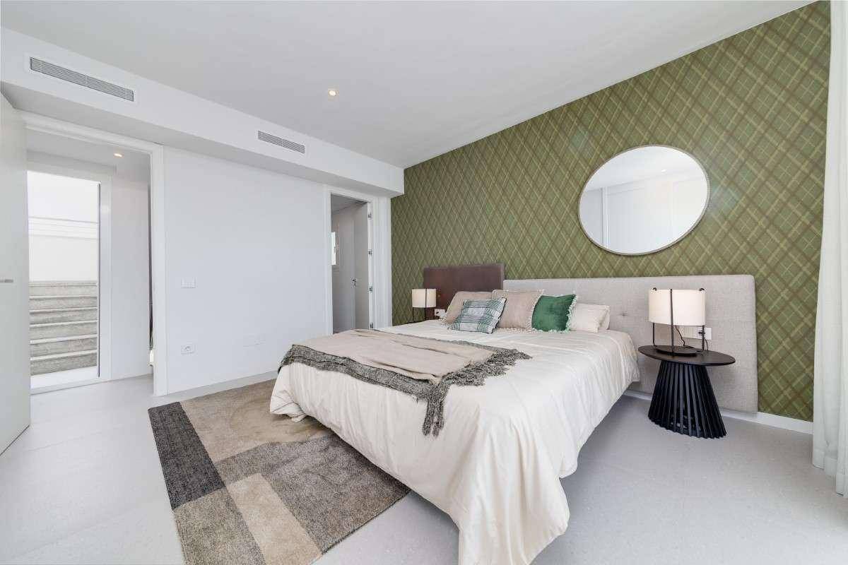 Stilvolles Schlafzimmer mit gemusterter grüner Wand, großem Bett und Zugang zu einem Bad.