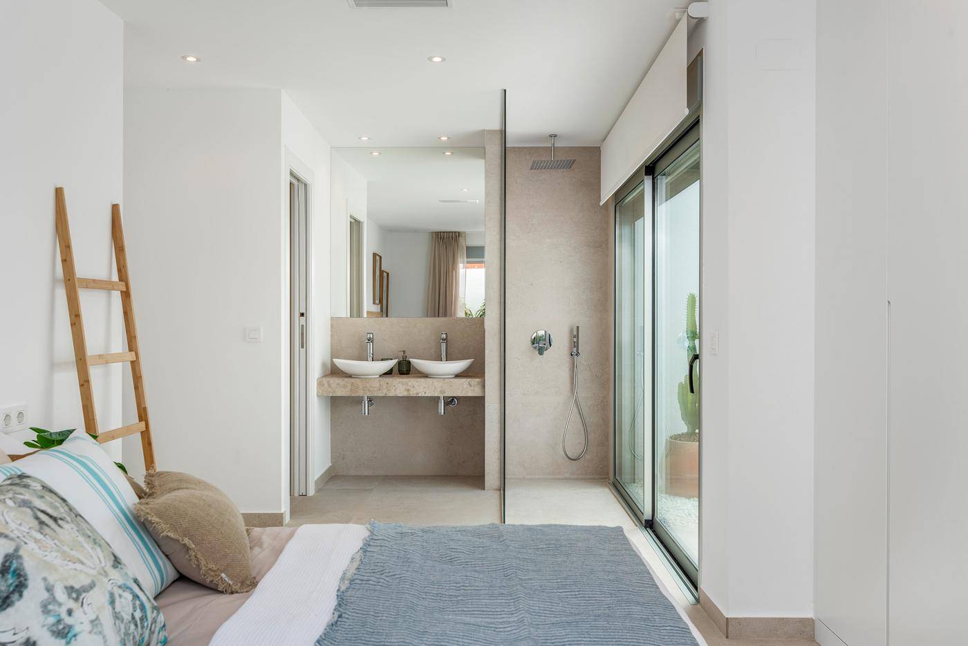 Schlafzimmer mit direktem Zugang zum modernen Badezimmer und Blick ins Grüne.