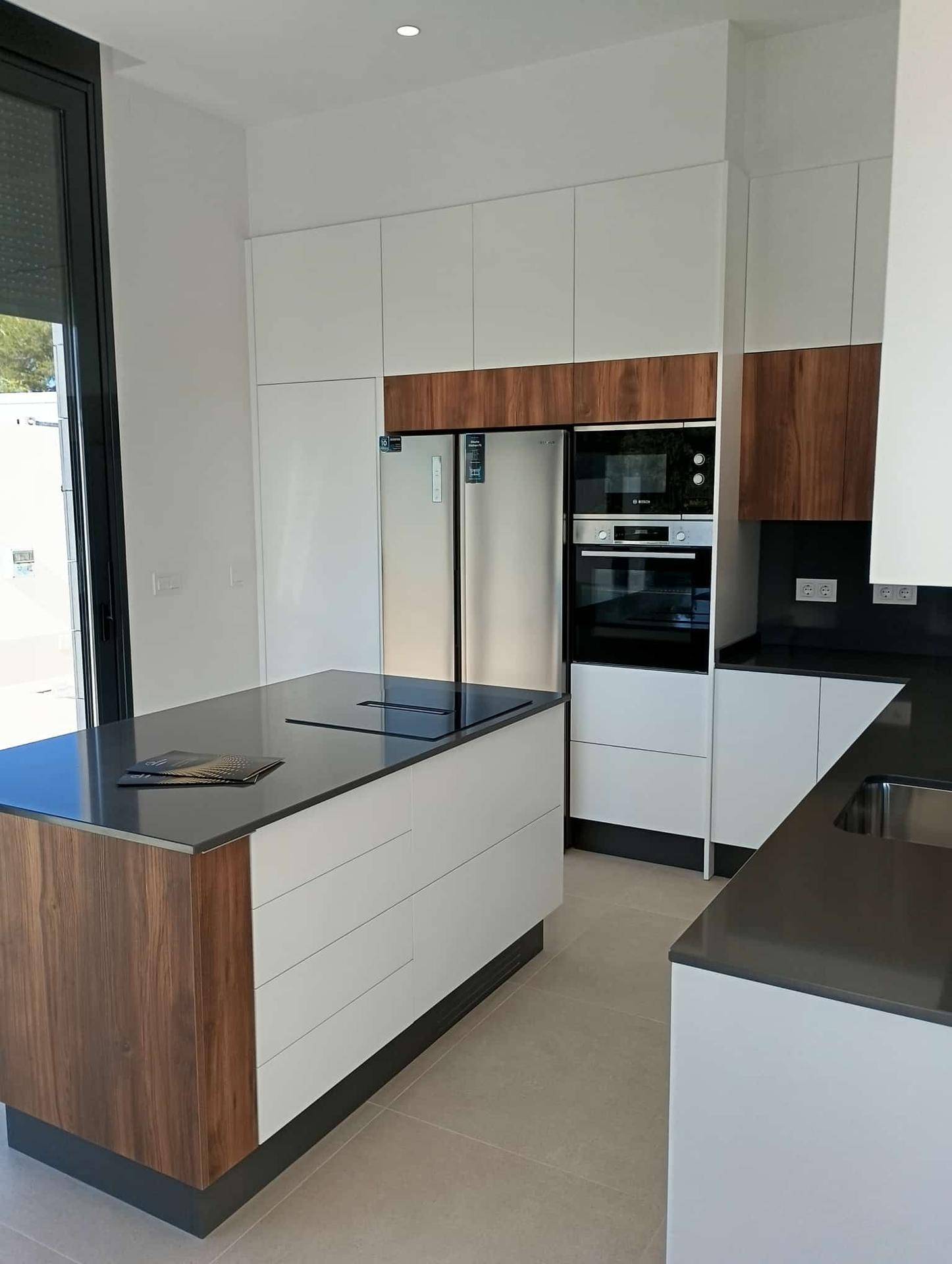Moderne Küche mit dunklen Arbeitsplatten, integrierten Geräten und viel Stauraum.