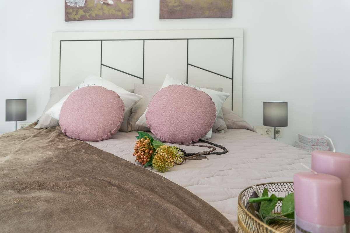 Gemütliches Schlafzimmer mit modernem Kopfteil, Nachttischen und dekorativen Kissen.