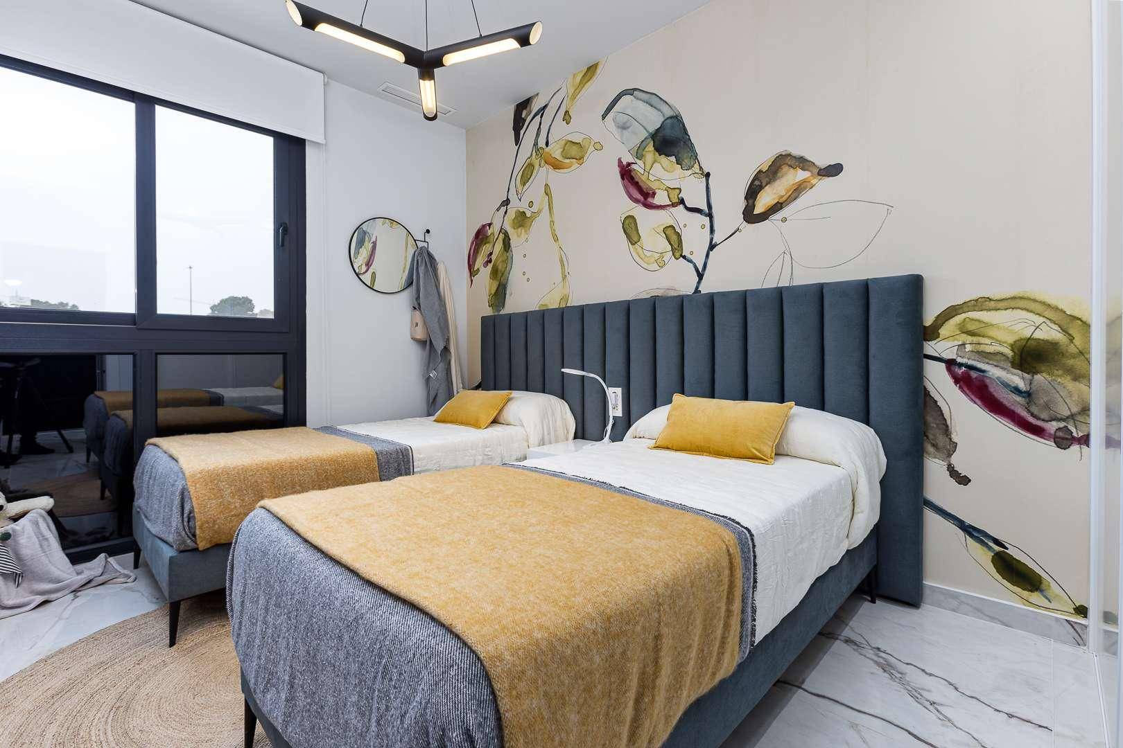 Helles Schlafzimmer mit großen Fenstern, zwei Einzelbetten und moderner Deckenleuchte.