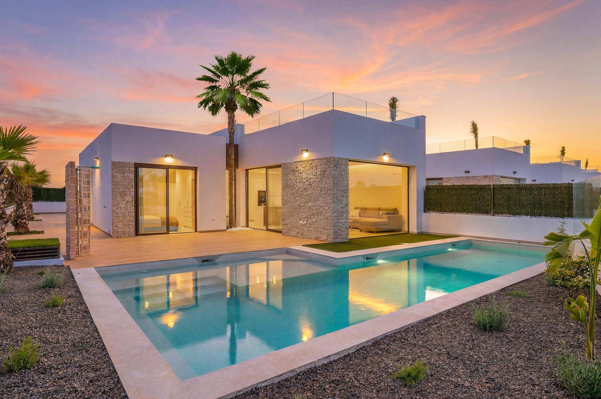 Moderne Villa mit großem Pool und raumhohen Fenstern, beleuchtet vom warmen Licht des Sonnenuntergangs.