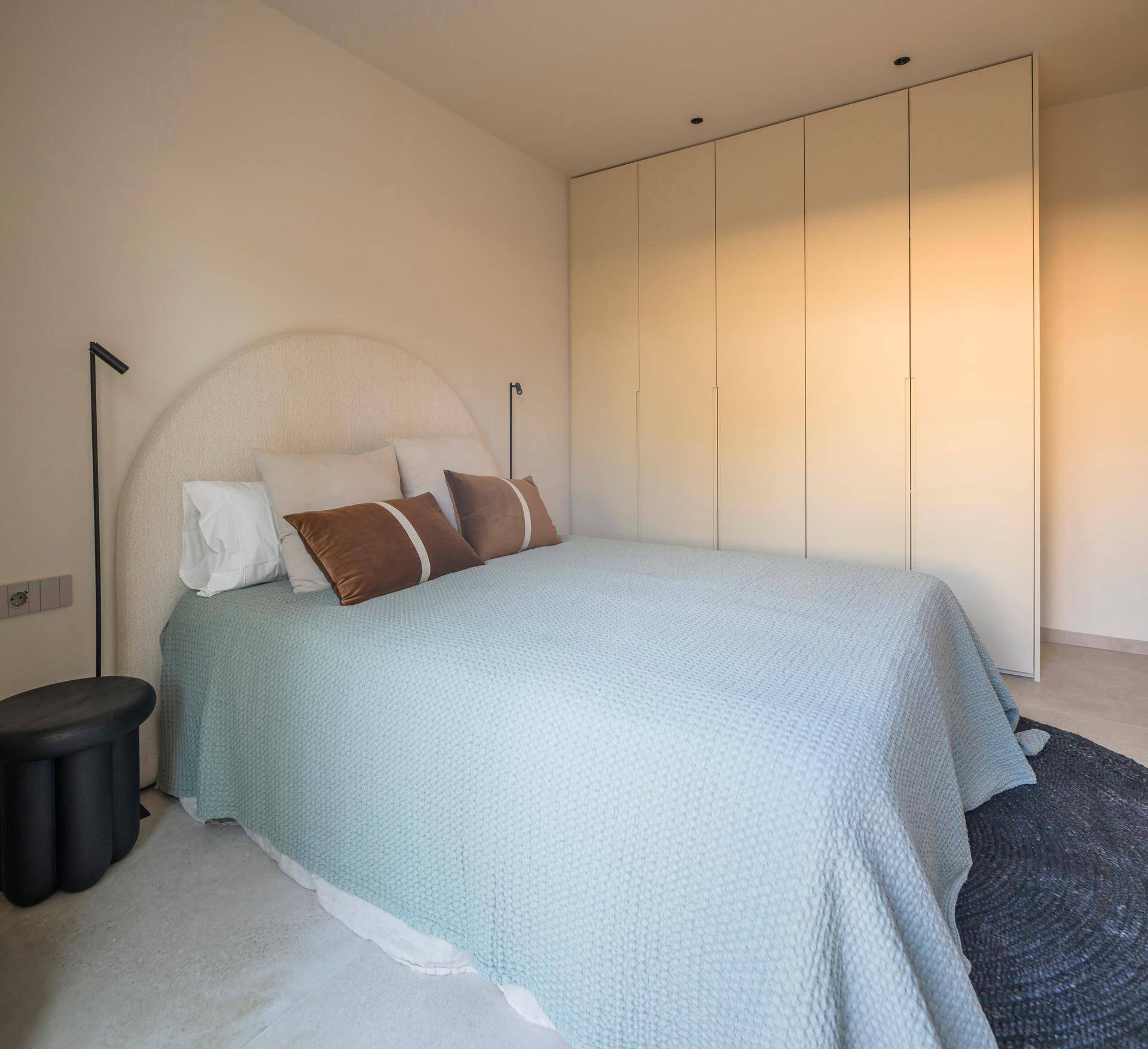 Heller Wohnbereich mit beigem Sofa, Holztisch und zwei schwarzen Korbstühlen, umgeben von transparenten Vorhängen.