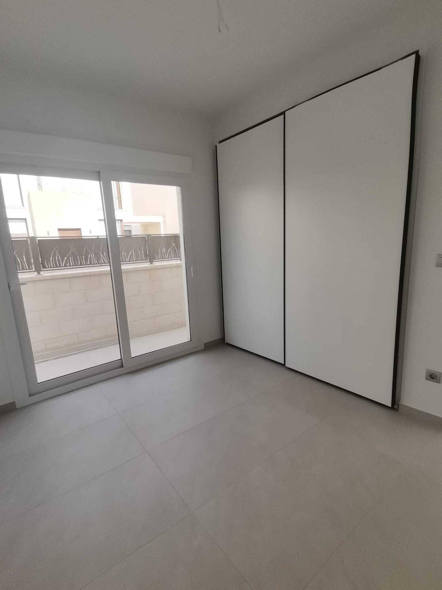 Helles Schlafzimmer mit Zugang zum Balkon und Einbauschrank, bereit zur Einrichtung und Nutzung.