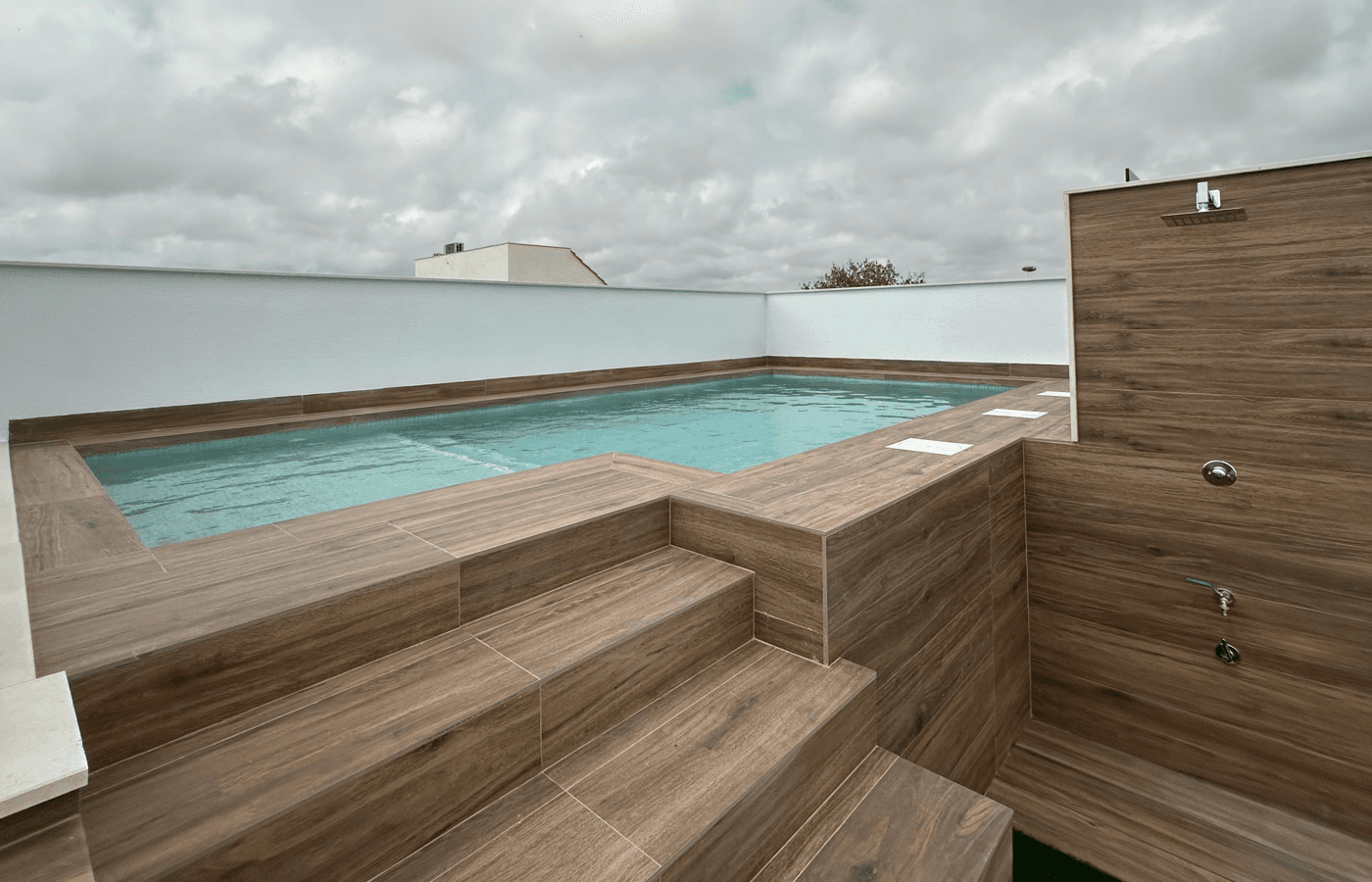 Dachterrasse mit privatem Pool und Außendusche unter bewölktem Himmel.